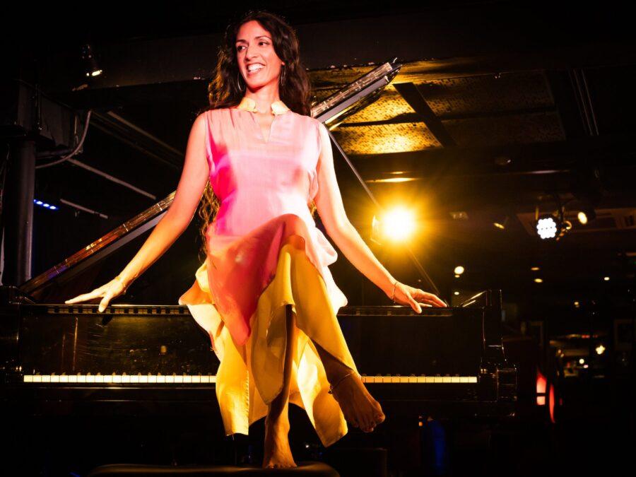 Zoe Rahman sits on top of a piano.